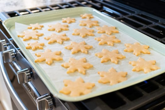 Letting delightful snowflake-shaped sugar cookies cool after baking, preparing them for festive Christmas gifts.