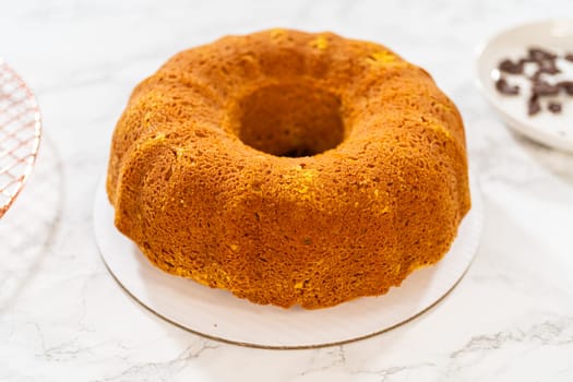 Icing the pumpkin bundt cake with cream cheese frosting and decorating it with chocolate leaves.