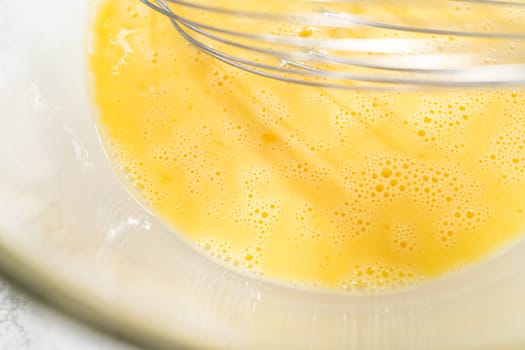 A close-up view of expertly blended ingredients in a large mixing bowl for a mouthwatering homemade pumpkin bundt cake.