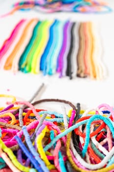 A vibrant collection of clay beads, neatly arranged by color on a white table, ready to inspire young crafters to create their own unique bracelets.