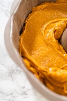 Pouring cake batter into a bundt cake pan, ready to bake a delicious homemade pumpkin bundt cake.