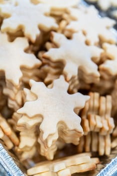 Carefully stacking the beautifully crafted snowflake-shaped sugar cookies into a foil pan, ready for freezing as delightful Christmas treats.
