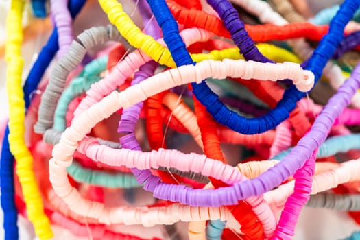 A vibrant collection of clay beads, neatly arranged by color on a white table, ready to inspire young crafters to create their own unique bracelets.