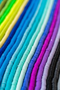 A vibrant collection of clay beads, neatly arranged by color on a white table, ready to inspire young crafters to create their own unique bracelets.
