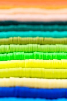A vibrant collection of clay beads, neatly arranged by color on a white table, ready to inspire young crafters to create their own unique bracelets.