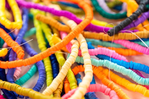 A vibrant collection of clay beads, neatly arranged by color on a white table, ready to inspire young crafters to create their own unique bracelets.