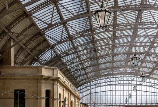 Windsor, UK - Apr 3, 2025 - The vintage iron glass roof with Lamps on the ceiling of Windsor Royal Shopping complex. Perspective view of Metallic framework arch roof with ceiling hanging lamp, Victorian Architecture, use it as your Wallpaper, Poster and Space for text, Selective focus.
