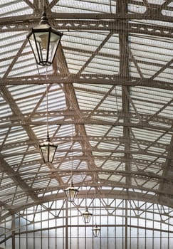 Windsor, UK - Apr 3, 2025 - The vintage iron glass roof with Lamps on the ceiling of Windsor Royal Shopping complex. Perspective view of Metallic framework arch roof with ceiling hanging lamp, Victorian Architecture, use it as your Wallpaper, Poster and Space for text, Selective focus.