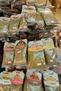 Crete, Greece - April 5, 2025: Display of herb mixes for cooking, including barbecue, pizza, curry, and salad blends, neatly packaged in vibrant bags with clear labels in a colorful shop setting.