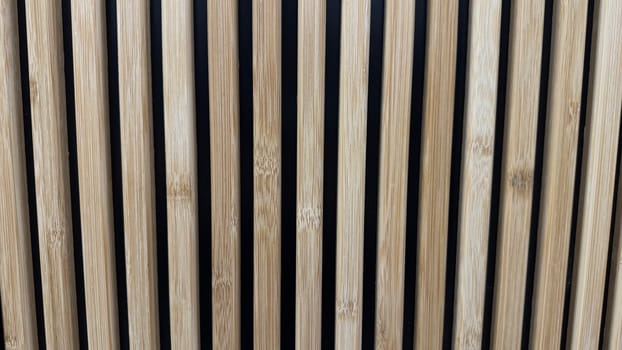 Close-up view of vertical wooden slats evenly spaced against a dark background, showcasing texture, alignment, and minimalism, suitable for modern and natural design concepts. Can be used like background.
