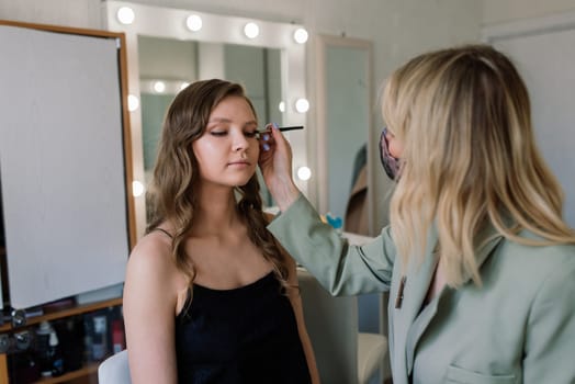 Makeup artist applies lipstick. Hand of make-up master, painting lips of a young beauty model.