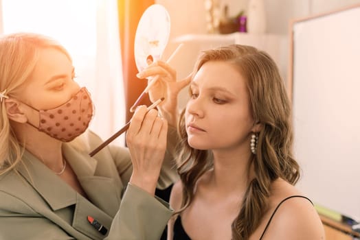 Makeup artist applies lipstick. Hand of make-up master, painting lips of a young beauty model.