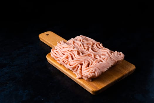 Minced meat on wood with fork. Fashionable photo of minced meat with space for text.