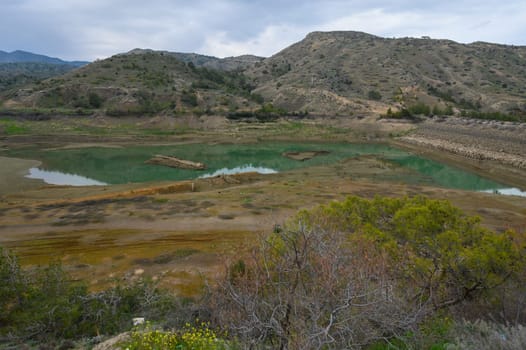 A tranquil vista unfolds with emerald waters reflecting the rugged hills.