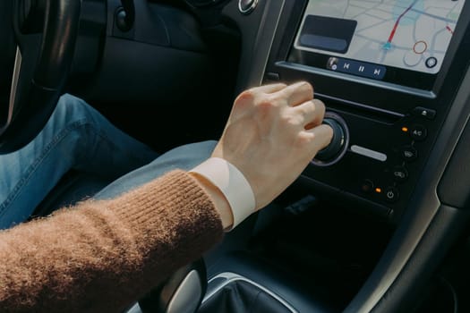 Portrait of hand of one young Caucasian guy in brown cashmere sweater shifting gear while driving car on sunny spring day, side view very close up with depth of field. Concept of hike time road trip, taxi services.