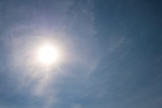 Sun shining through wispy clouds in a clear blue sky, creating a beautiful natural background