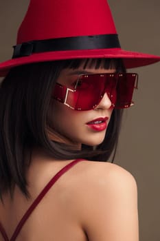 Woman, red dress, red fedora, sunglasses a stylish woman in a vibrant red dress and matching fedora hat with sunglasses on her head, showcasing a confident and fashionable look