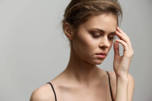 A serene young woman with natural makeup and a simple outfit, lost in thought, embodying a sense of vulnerability and introspection in a minimalistic setting.
