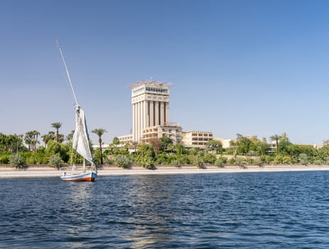 Aswan, Egypt - 4 November 2024: Movenpick Hotel in Elephantine, by the Nile. Felluca sails by the resort