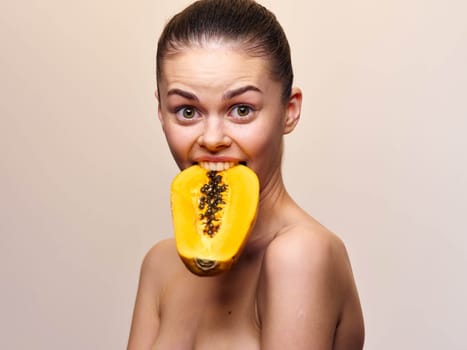 Beautiful woman holding a papaya fruit in front of her mouth with a seductive gaze, isolated on white background