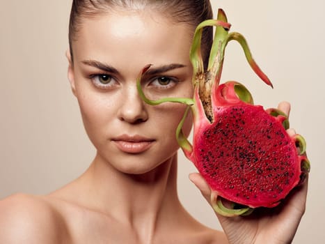 Beautiful young woman with dragon fruit facial mask, closeup beauty portrait on beige background, organic skincare concept