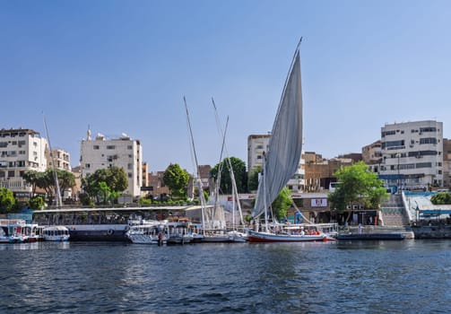 Aswan, Egypt - 4 November 2024: Felucca leaves the dock with other tour boats alongside for a cruise on the Nile
