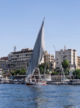 Aswan, Egypt - 4 November 2024: Felucca leaves the dock with other tour boats alongside for a cruise on the Nile