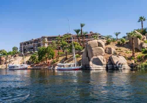 Aswan, Egypt - 4 November 2024: Felucca sailing boat docked alongside the Nile by the Old Cataract Hotel