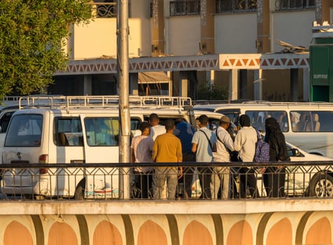 Aswan, Egypt - 4 November 2024: Locals getting on a local transport bus at the depot in Aswan for journey home