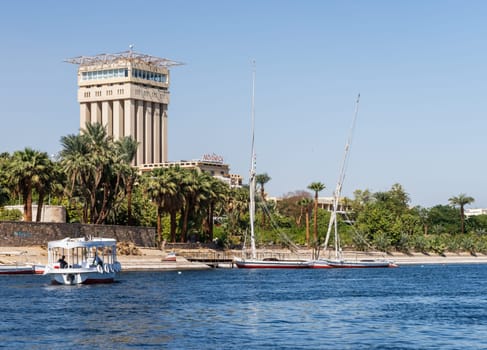 Aswan, Egypt - 4 November 2024: Movenpick Hotel in Elephantine, by the Nile. Felluca docked by the resort