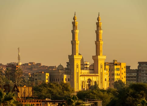 The setting sun illuminates a majestic mosque in Aswan, Egypt with warm light on ts iconic minarets.
