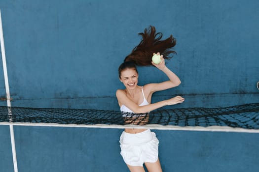 An energetic sports scene featuring a happy Asian woman playing tennis, dressed in a sporty outfit The dynamic blue backdrop and bright tennis ball amplify the lively atmosphere