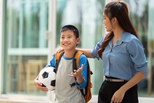 A smiling boy shares his thoughts with a teacher after class, excited about the upcoming school year and soccer activities.