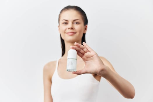 Young woman confidently holding a skincare bottle in front of her, showcasing a clean and minimalist aesthetic The white background enhances the focus on the product, promoting beauty and health