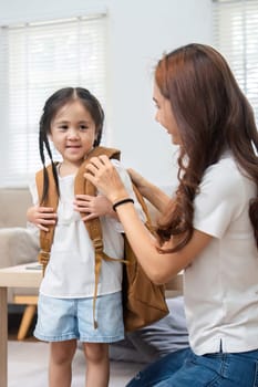 As the little girl prepares for her first day at school, her mother lovingly helps her with a backpack, creating cherished memories before the new adventure begins.