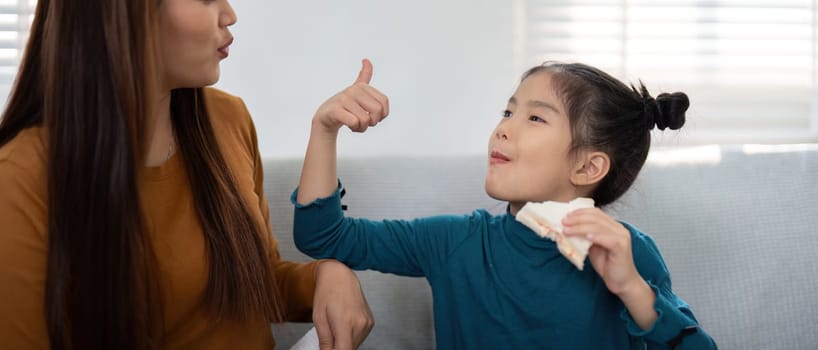 The mother and daughter enjoy a light-hearted moment, sharing a snack and excitement as they prepare for the upcoming school day.