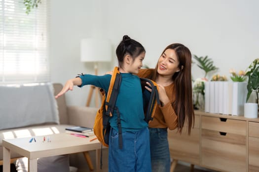 A caring moment as the mother helps her daughter put on her backpack, filled with supplies for the school day ahead.