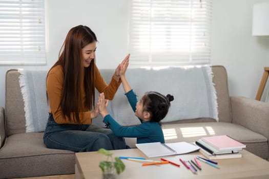 A mother and her daughter share laughter during a fun hand-clapping game, promoting joy and connection through playful interactions.