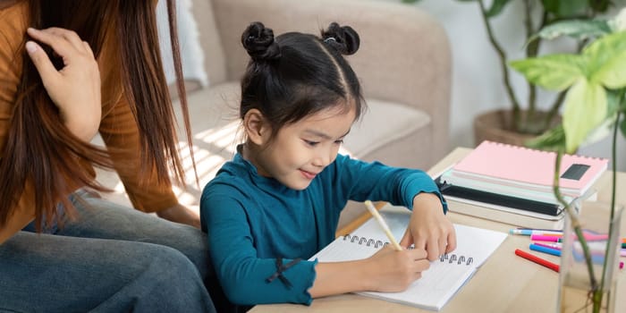 With her caregiver's help, a little girl focuses on her writing, demonstrating enthusiasm for learning and the joys of creativity.