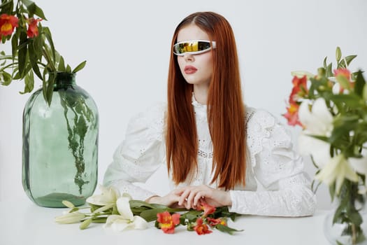 A fashionable model showcases a chic look with long hair and trendy sunglasses, surrounded by vibrant flowers in a minimalist setting, perfect for spring and summer fashion themes
