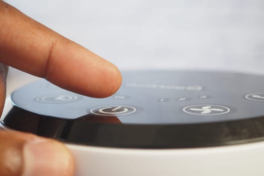 A person is interacting with a sleek device, adjusting the settings calmly.