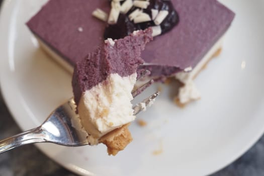 Creamy dessert with purple layers and a cherry topping enjoyed at a cafe