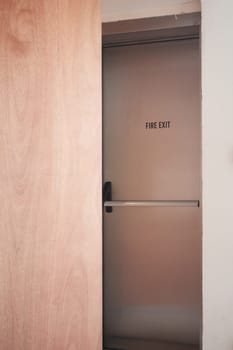 A fire exit door is slightly ajar in a clean hallway setting.
