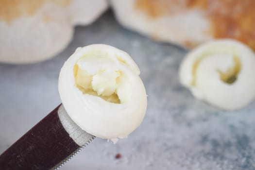 Smooth butter curls rest on a knife ready for spreading on toast.