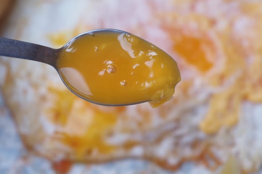 Spoon holds a rich golden egg yolk above a cooking surface.