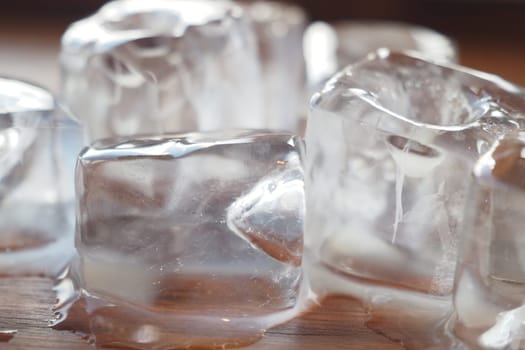 Ice cubes slowly melting on a wooden surface create a refreshing atmosphere.