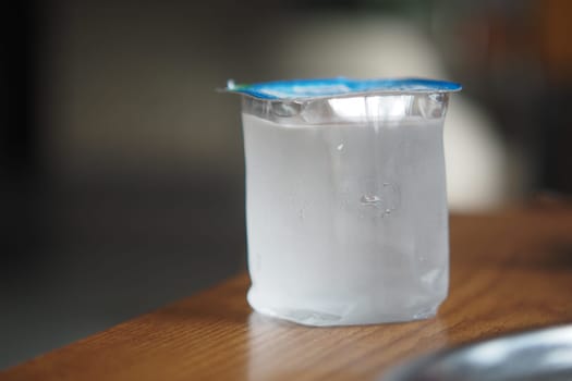 A container filled with water sits on a wooden table, exuding moisture.