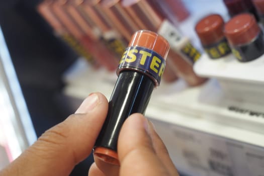 closeup of woman holding tester lipstick .