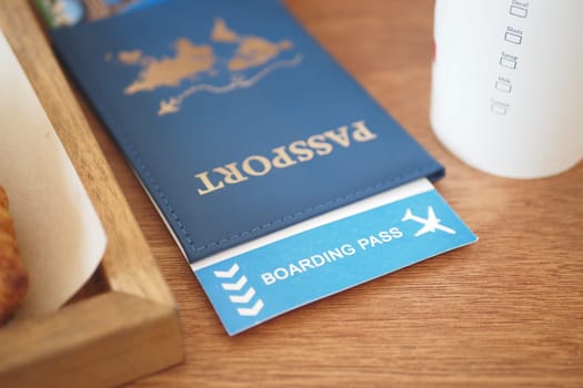 A passport and boarding pass are placed on a wooden table, ready for travel.