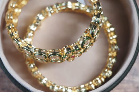 Three elegant gold bangles are arranged neatly inside a jewelry box.